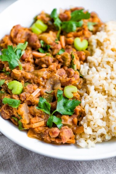 Plate of red beans and rice topped with fresh celery ad parsley.