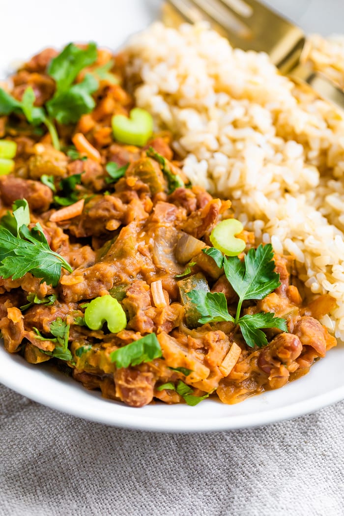 Plate of red beans and rice topped with fresh celery ad parsley.