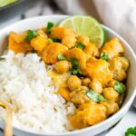 Bowl with half rice and half sweet potato chickpea curry topped with cilantro and lime.