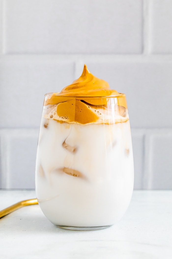 Glass of iced non-diary milk topped with coffee foam.