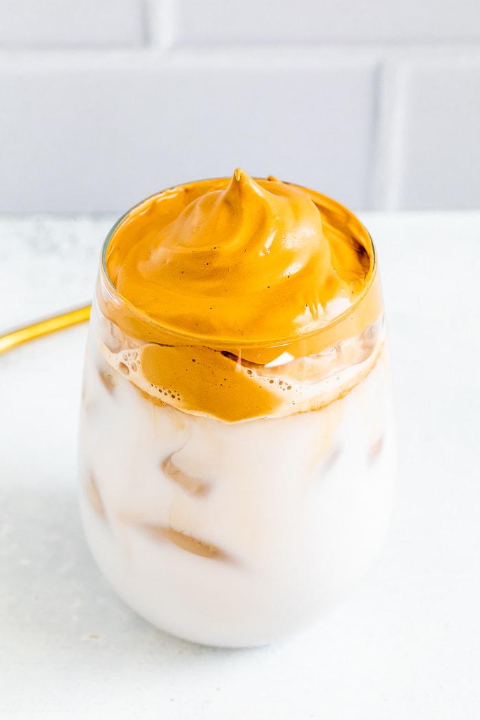 Glass of iced non-diary milk topped with coffee foam.