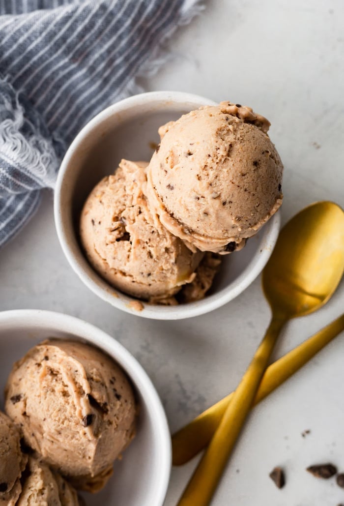 Two bowls with scoops of chocolate banana ice cream with two gold spoons.