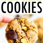 Hand holding an almond flour cookie with dark chocolate chunks and pistachios