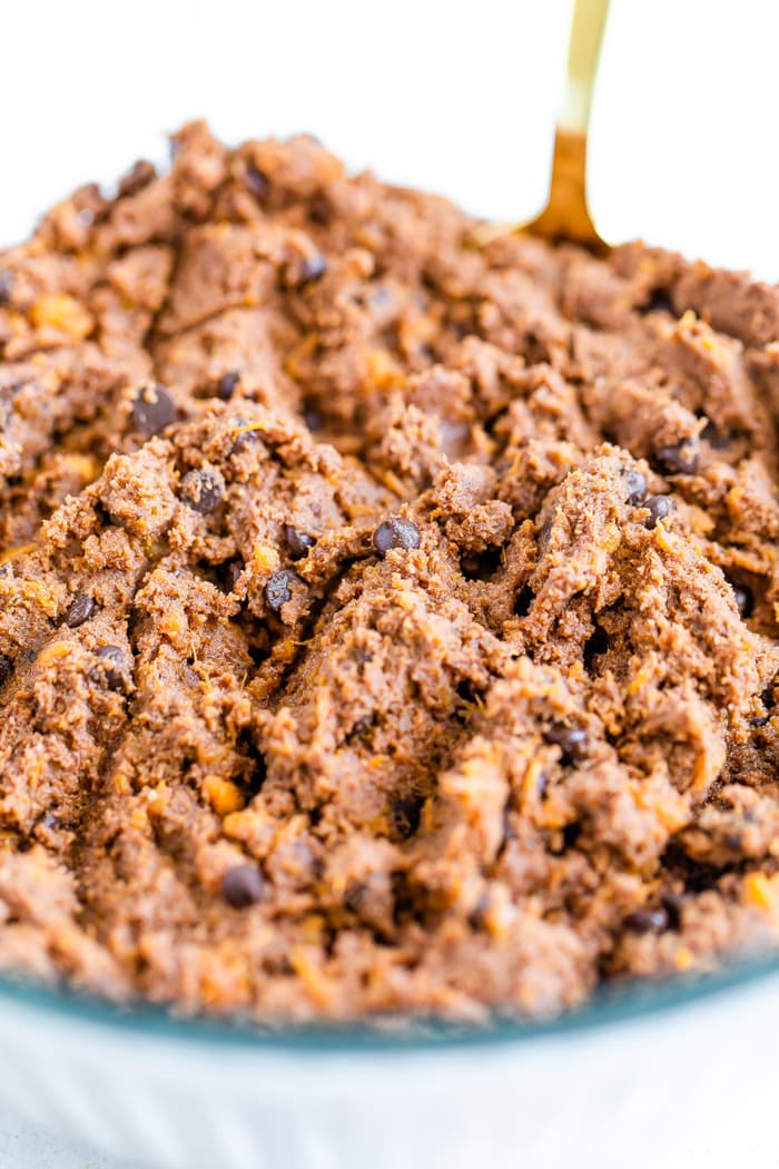 Mixing bowl full of sweet potato brownie batter and a mixing spoon.