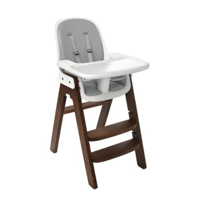 OXO Tot Sprout high chair with grey seat and walnut wooden legs on white background.