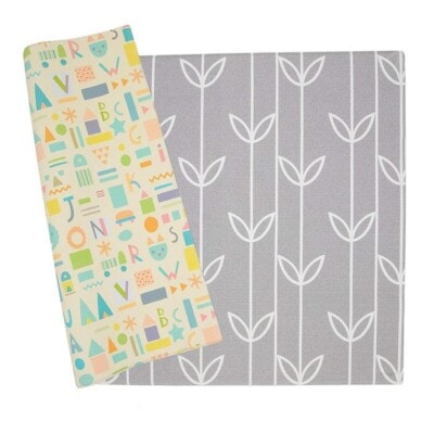 Reversible baby mat with a colorful pastel print on one side and a grey leaf print on the other. Play mat is pictured on a white background.
