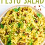 Bowl of pesto spaghetti squash salad topped with parsley and sun-dried tomatoes.