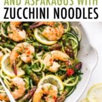 White sauté pan with zucchini noodles, asparagus and shrimp topped with red pepper flakes.