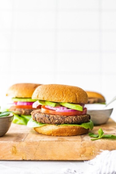 Sweet potato black bean burger on a bun with avocado, tomato, onion and lettuce.