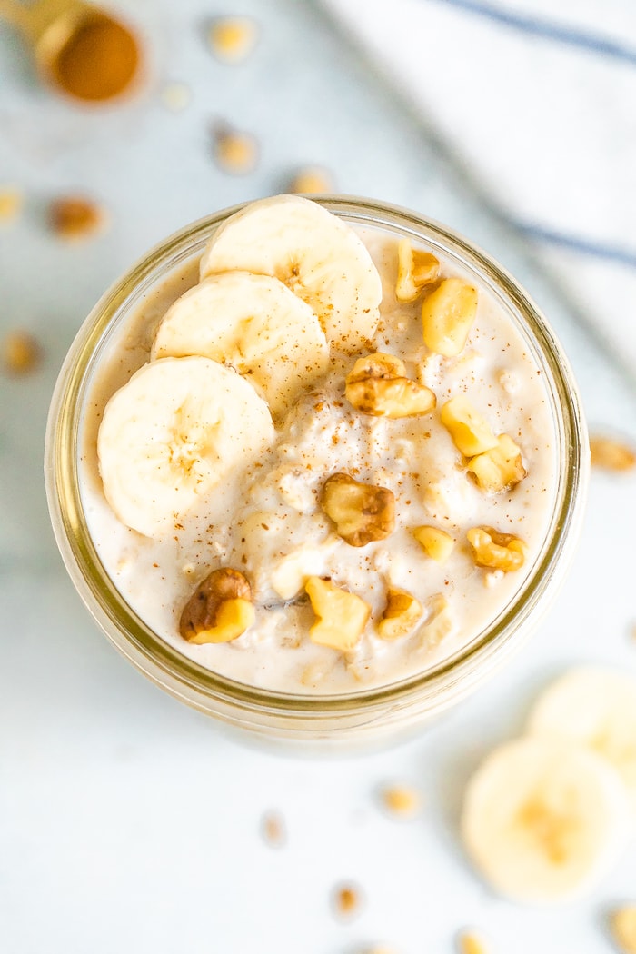 Overhead shot of a mason jar with banana bread overnight oats, topped with banana slices and walnuts.