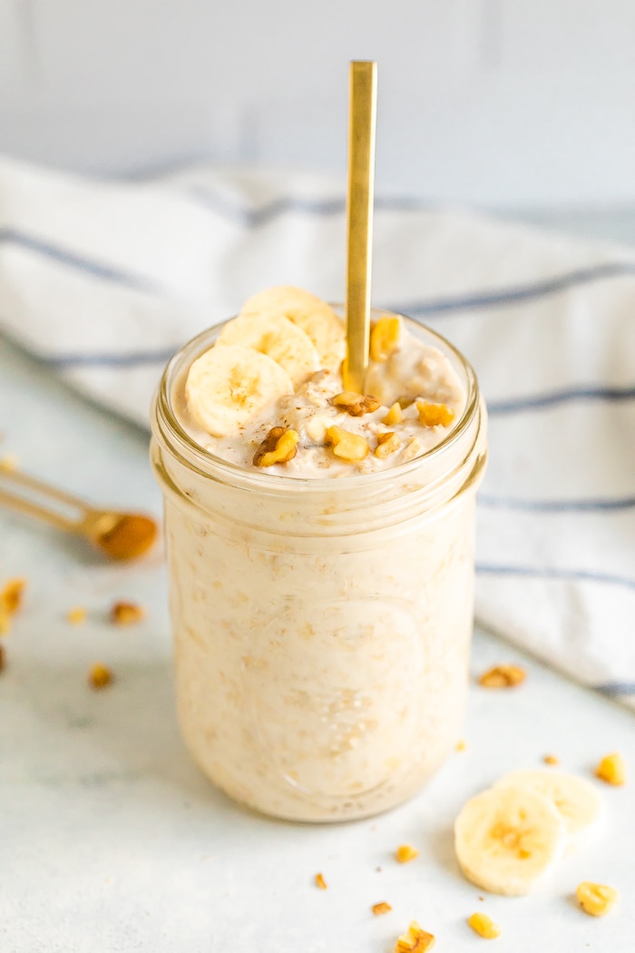 Mason jar with banana bread overnight oats, topped with banana slices and walnuts.