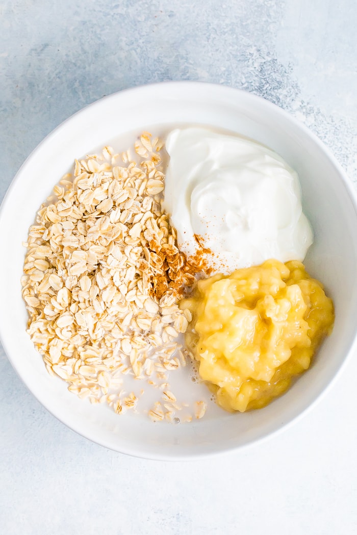 Ingredients for banana bread overnight oats in a white bowl before mixing.