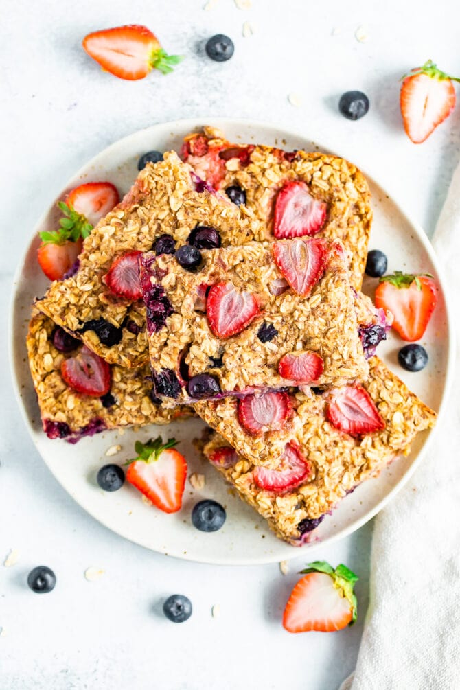 Oatmeal bars made with strawberries and blueberries stacked on a plate.