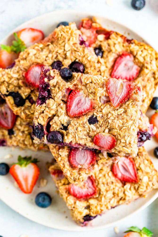 Oatmeal bars made with strawberries and blueberries stacked on a plate.