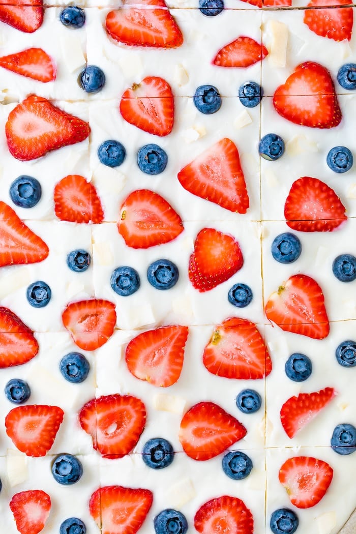 Frozen yogurt bark topped with blueberries, strawberries and coconut flakes, and cut into squares.