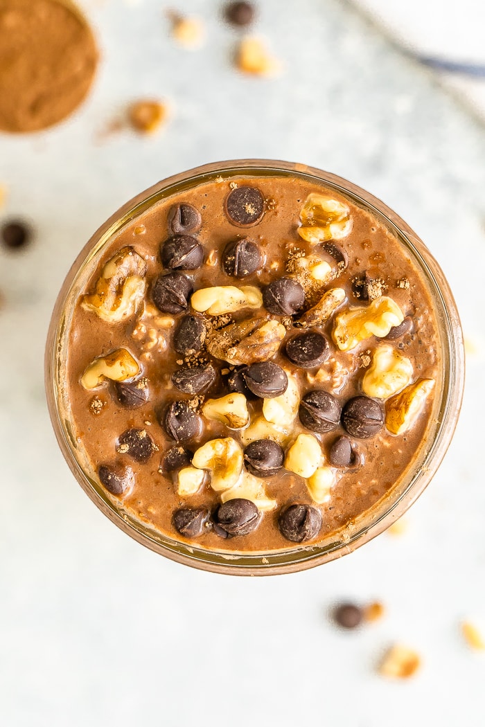 Overhead shot of chocolate brownie batter overnight oats in a mason jar. Topped with walnuts and chocolate chips.