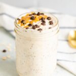 Chocolate chip overnight oats in a mason jar. Topped with chocolate chips and a peanut butter drizzle.
