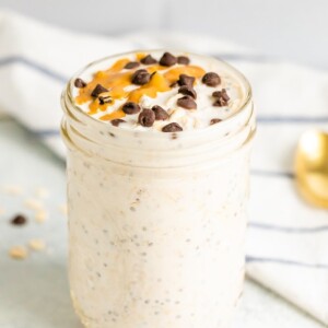 Chocolate chip overnight oats in a mason jar. Topped with chocolate chips and a peanut butter drizzle.