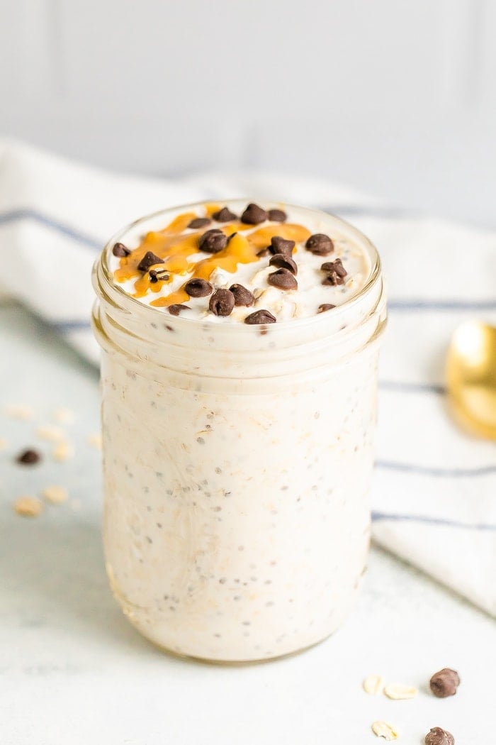 Chocolate chip overnight oats in a mason jar. Topped with chocolate chips and a peanut butter drizzle.