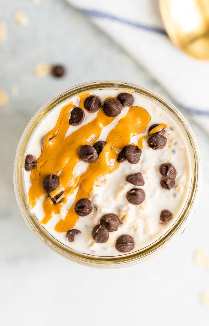 Overhead shot of chocolate chip overnight oats in a mason jar. Topped with chocolate chips and peanut butter.