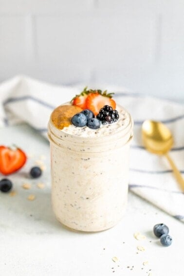 Basic overnight oats in a mason jar with berries and peanut butter on top.