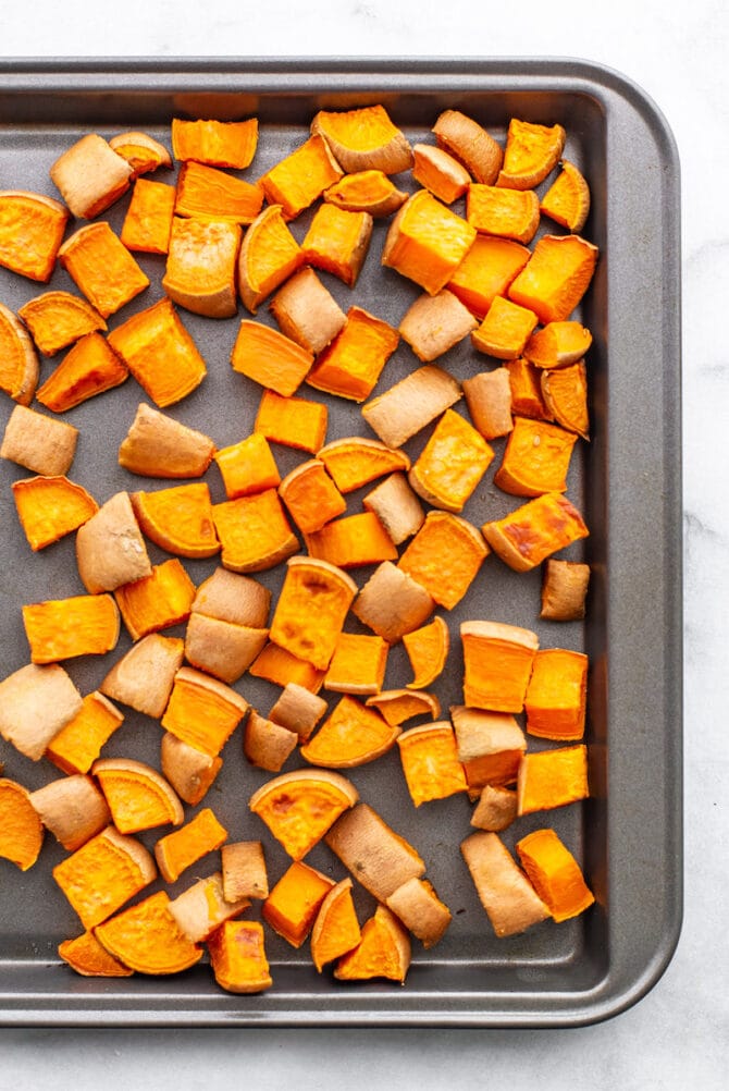 Sweet potato chunks roasted on a sheet pan.