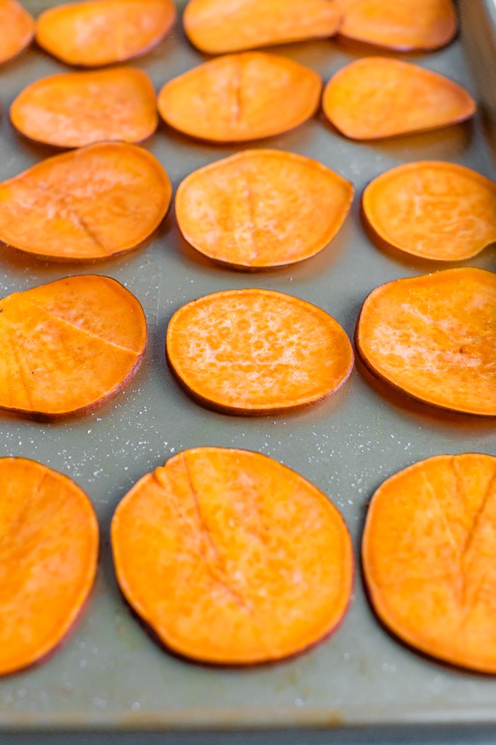 Thin slices of sweet potatoes on a cookie sheet.