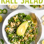 Close up photo of a white bowl and gold fork with a Mexican street corn and kale grilled chicken salad. The salad is topped with slices of avocado. Ingredients in the salad are sprinkled on the table.