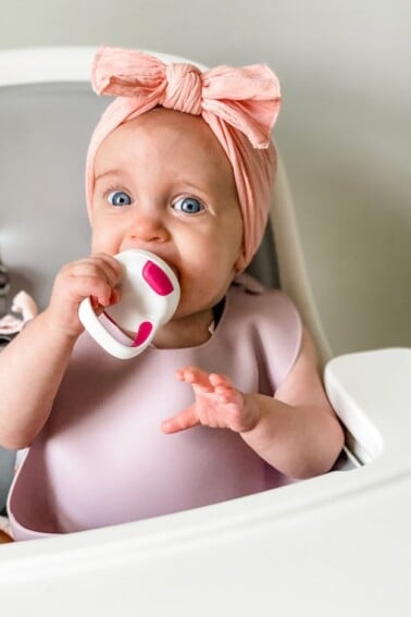 Baby girl with a bow using OXO self feeder
