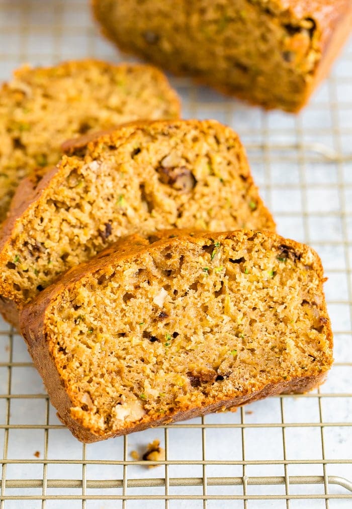 Close up photo of three thick slices of zucchini bread on a gold cooling rack.