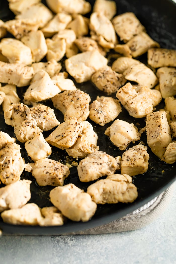 Skillet with bite size pieces of seasoned chicken cooked in the skillet.