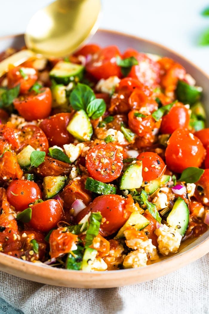 Close up photo of a tomato cucumber salad in a serving bowl.