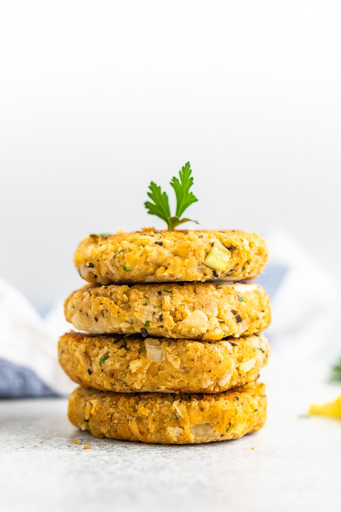 Pila di 4 torte di granchio vegan condite con un rametto di prezzemolo fresco.