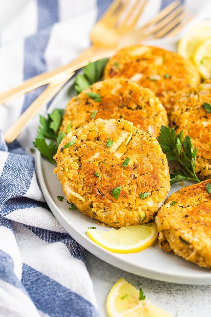 Plato con pasteles de cangrejo veganos adornados con rodajas de perejil y limón.