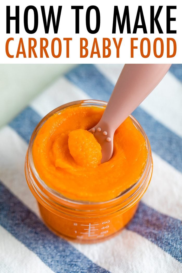 Glass baby food jar with carrot puree with an ezpz spoon dipped in.