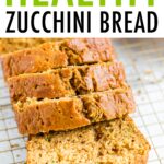 Loaf of zucchini bread with 4 thick slices cut on a gold wire cooling rack.