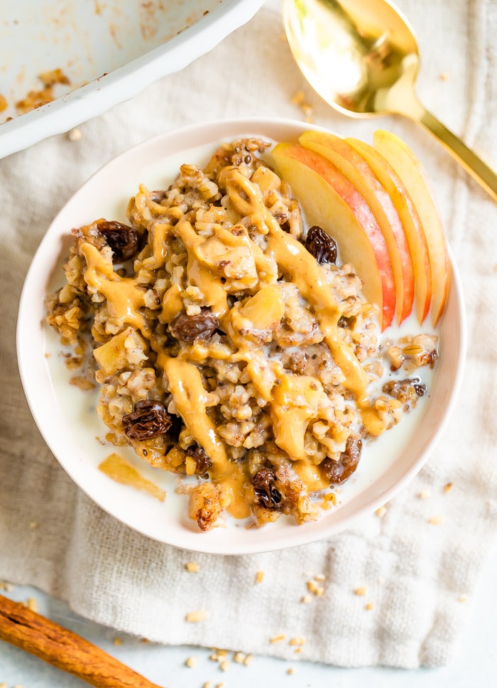 Overhead shot of baked apple steel cut oatmeal in a pink bowl with peanut butter drizzled on top.