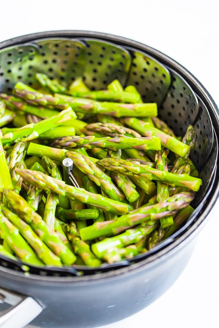 Asparagus spears in a steamer basket in a pot. 