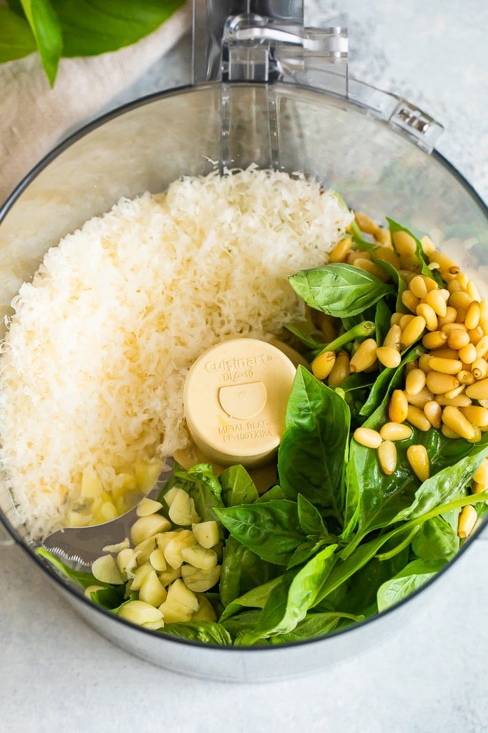 Food processor with parmesan, pine nuts, fresh basil, garlic and olive oil.