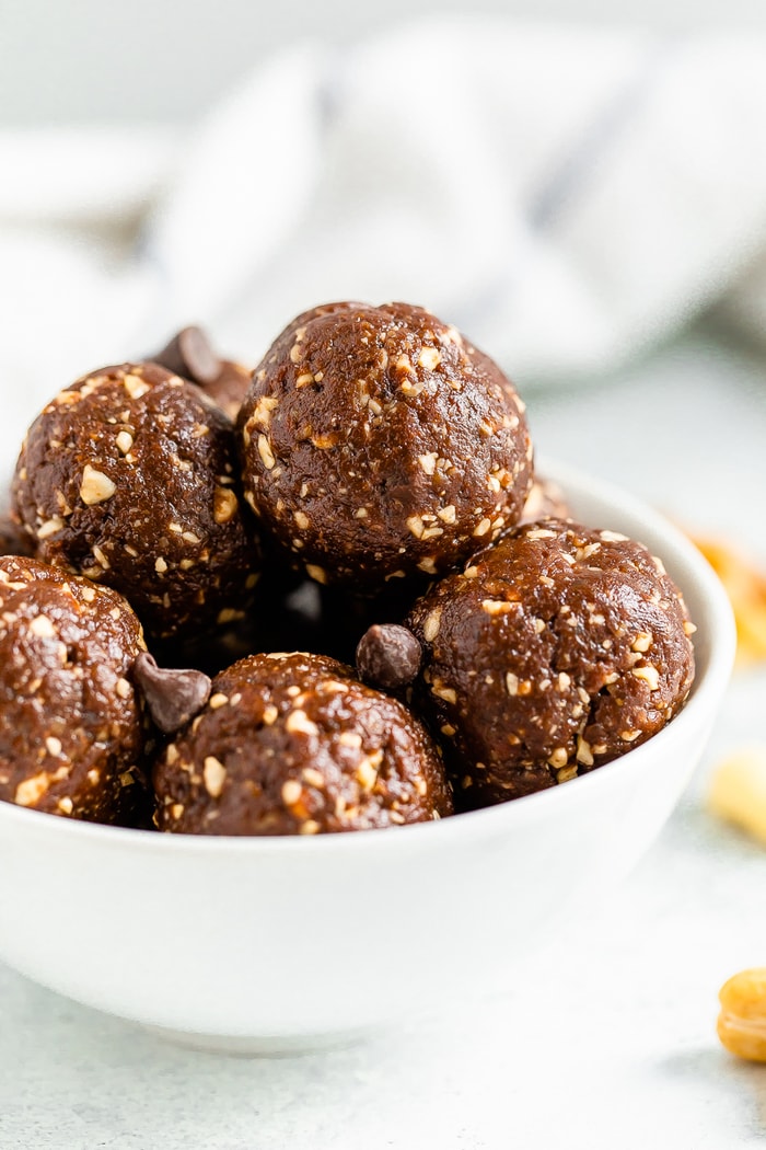 White bowl full of brownie energy balls sprinkled with chocolate chips.