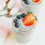 Chia pudding in mason jars with blueberries and strawberries on top.