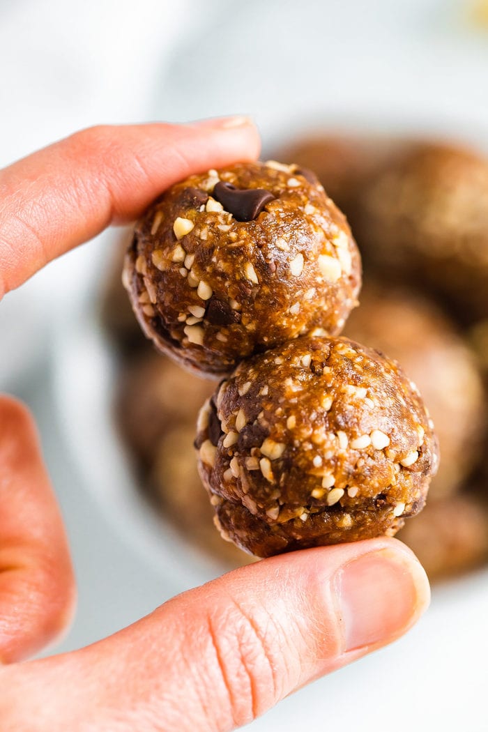 Hand holding two coconut chocolate chip energy balls.