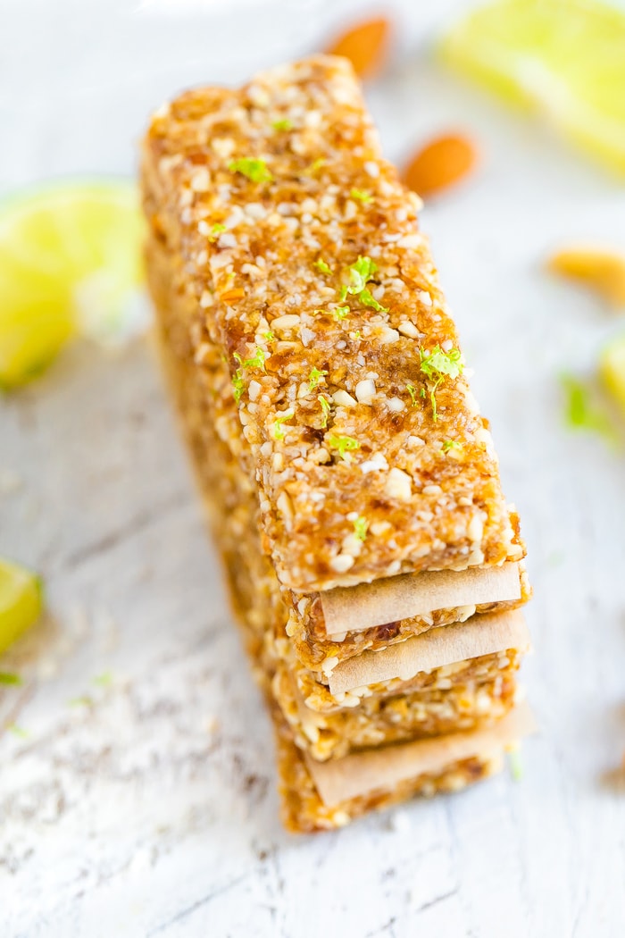 Key lime pie Larabars stacked with parchment in between each. The top bar has lime zest on top.