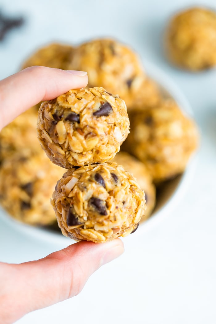 Hand holding two peanut butter chocolate chip energy balls.