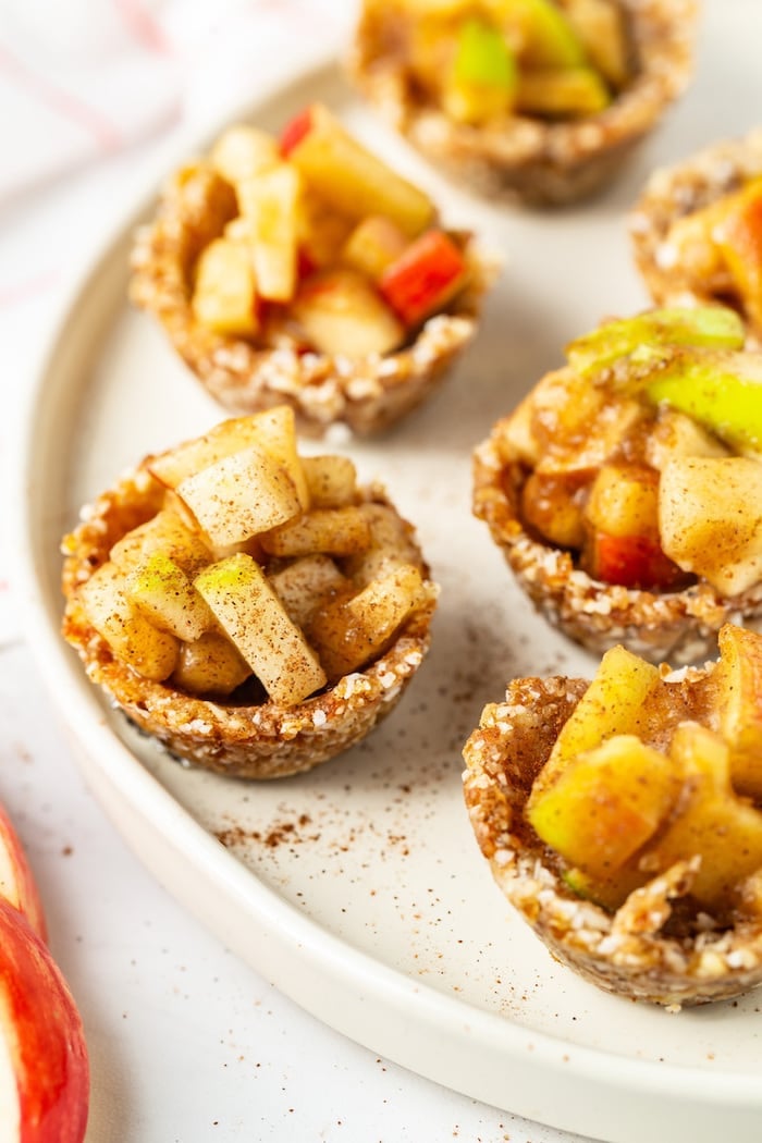 Close up photo of raw mini apple pies on a plate.
