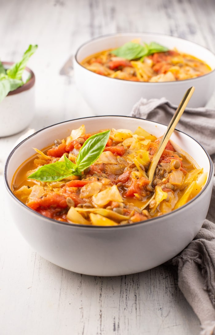 Cabbage lentil soup portioned into one bowl with gold spoon.