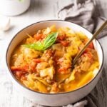 Cabbage lentil soup portioned into one bowl with gold spoon in soup.