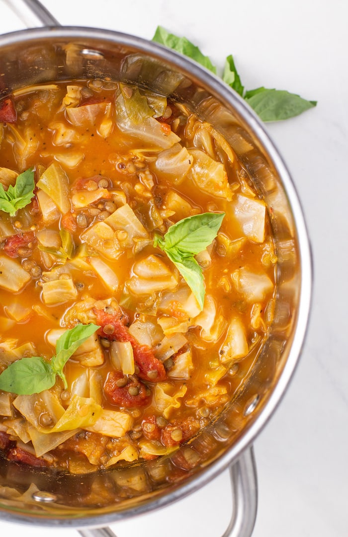 Cabbage lentil soup in a stock pot with fresh basil on top.