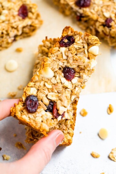 Hand holding one cranberry granola bar.