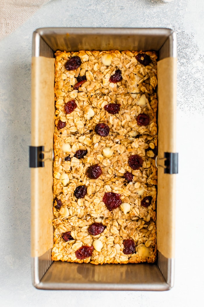 Granola bar mixture in a loaf pan lined with parchment.